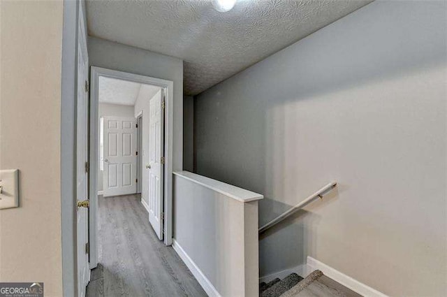 2892 Norfair Loop NE, Lithonia, GA 30038 - corridor featuring baseboards, a textured ceiling, an upstairs landing, and wood finished floors