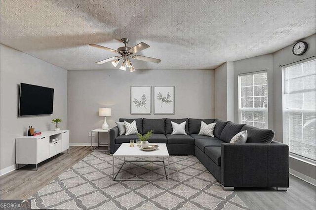 2892 Norfair Loop NE, Lithonia, GA 30038 - living room featuring a textured ceiling, light wood-style flooring, baseboards, and a ceiling fan