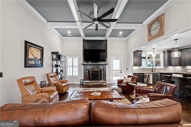 living area featuring beam ceiling, coffered ceiling, wood finished floors, ceiling fan, and a fireplace