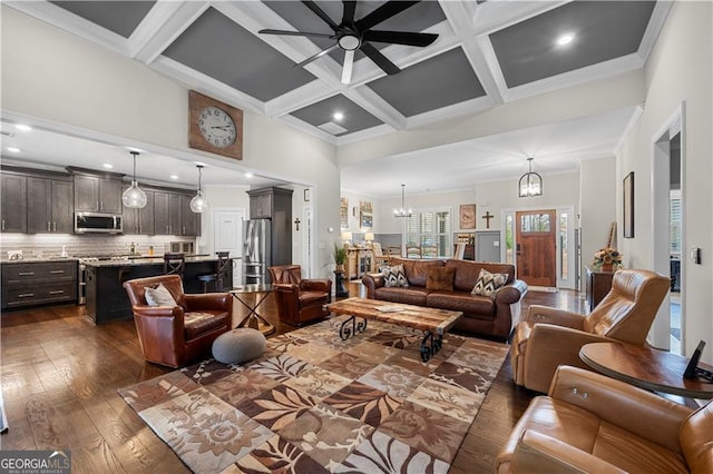 living room featuring dark wood-style floors, beam ceiling, coffered ceiling, ceiling fan with notable chandelier, and a high ceiling