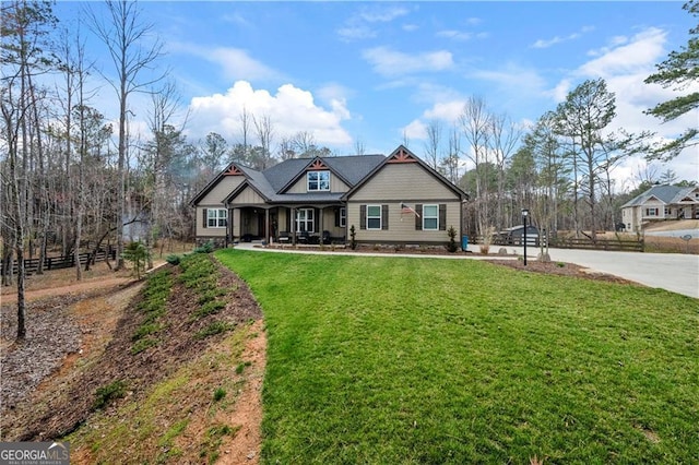 craftsman house with a front lawn, driveway, fence, and covered porch