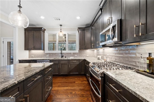 kitchen with light stone counters, stainless steel appliances, a sink, dark brown cabinetry, and dark wood-style flooring