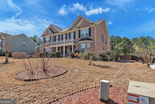 view of front of house with a balcony, brick siding, and fence