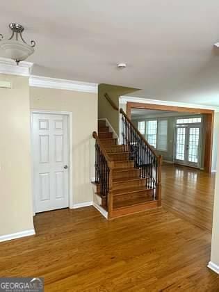 stairs featuring ornamental molding, baseboards, and wood finished floors