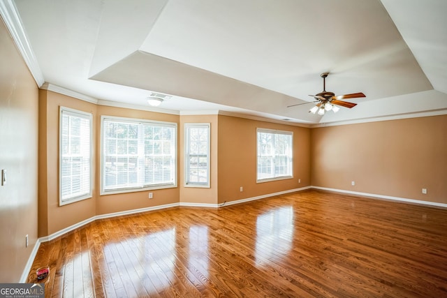 unfurnished room featuring hardwood / wood-style flooring, ornamental molding, baseboards, and a raised ceiling