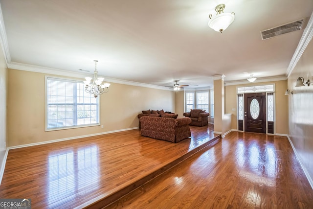 foyer with wood finished floors, baseboards, ceiling fan with notable chandelier, visible vents, and ornamental molding