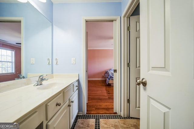bathroom with baseboards, crown molding, tile patterned floors, and vanity