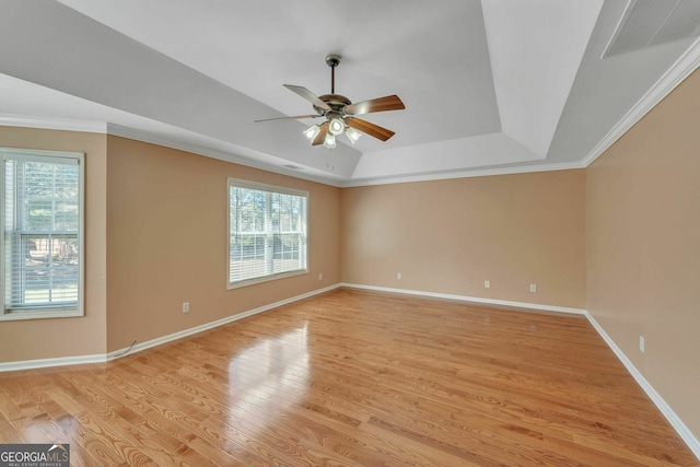 unfurnished room featuring a tray ceiling, visible vents, plenty of natural light, and light wood-type flooring
