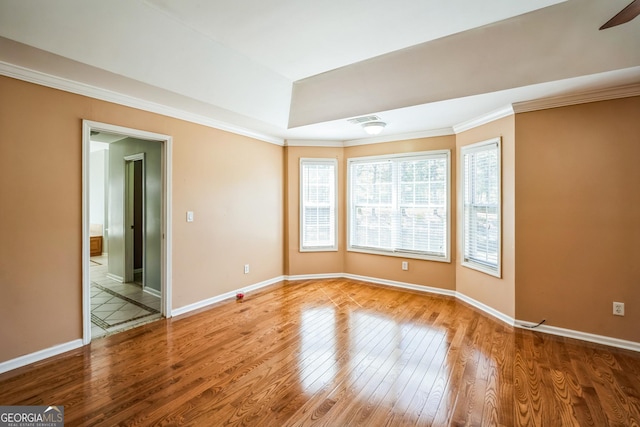 unfurnished room featuring baseboards, visible vents, wood finished floors, and ornamental molding