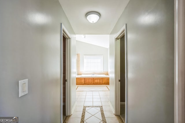 hall with light tile patterned flooring and lofted ceiling