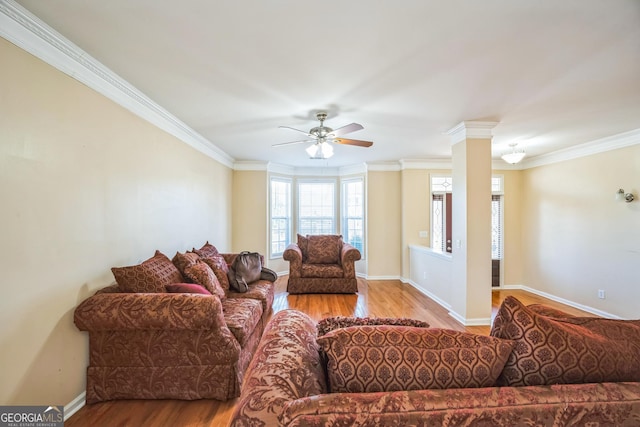 living area with baseboards, crown molding, wood finished floors, and ceiling fan