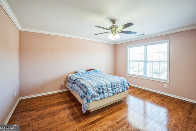 bedroom featuring crown molding, a ceiling fan, wood finished floors, baseboards, and visible vents