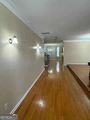 hall featuring baseboards, crown molding, and wood finished floors