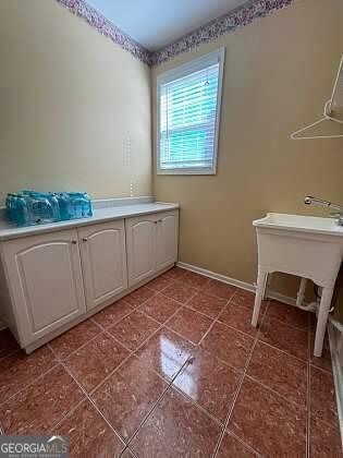 washroom with baseboards and tile patterned floors