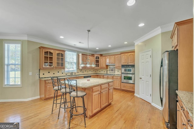 kitchen featuring a kitchen bar, light wood-type flooring, backsplash, appliances with stainless steel finishes, and glass insert cabinets