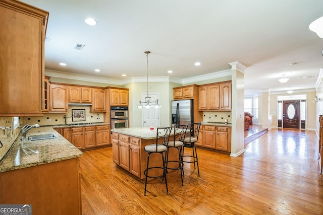 kitchen with a sink, a kitchen island, brown cabinets, stainless steel appliances, and visible vents