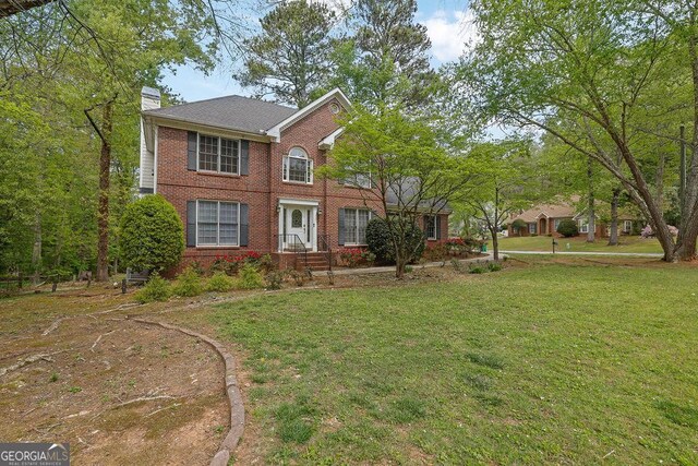 7037 Waters Edge Dr, Stone Mountain, GA 30087 - colonial inspired home with a chimney, brick siding, and a front yard