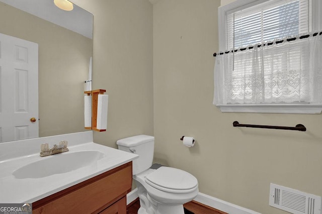7037 Waters Edge Dr, Stone Mountain, GA 30087 - half bathroom featuring toilet, baseboards, visible vents, wood finished floors, and vanity