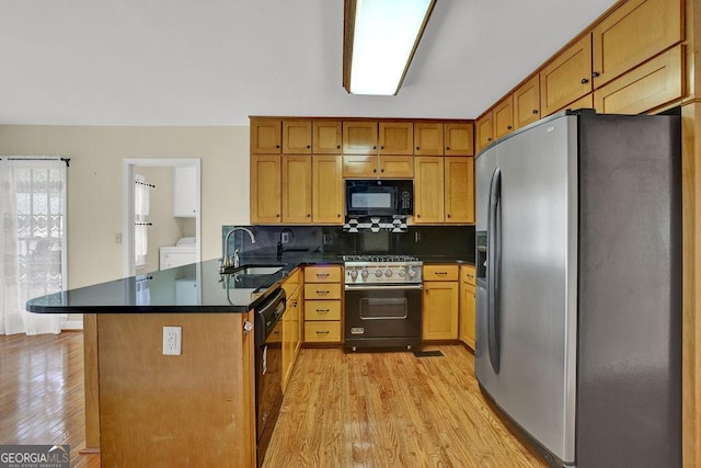 7037 Waters Edge Dr, Stone Mountain, GA 30087 - kitchen with dark countertops, a sink, black appliances, light wood-type flooring, and a peninsula