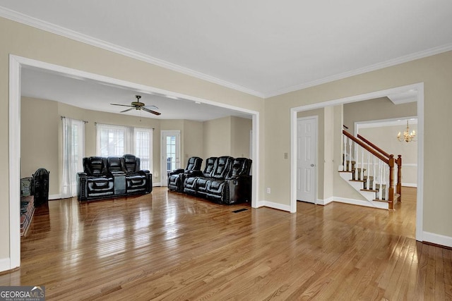 7037 Waters Edge Dr, Stone Mountain, GA 30087 - living room with stairway, crown molding, wood finished floors, ceiling fan with notable chandelier, and baseboards