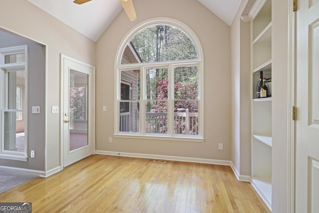 unfurnished dining area featuring wood finished floors, baseboards, a ceiling fan, and lofted ceiling