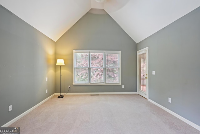 empty room with light carpet, high vaulted ceiling, and baseboards