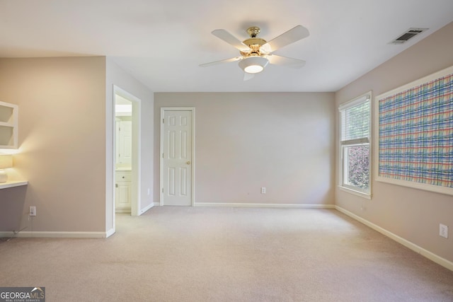 interior space with light colored carpet, baseboards, ensuite bathroom, and visible vents