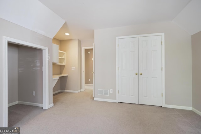 unfurnished bedroom featuring visible vents, baseboards, a closet, vaulted ceiling, and light colored carpet