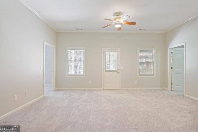 spare room with crown molding, ceiling fan, light colored carpet, and baseboards