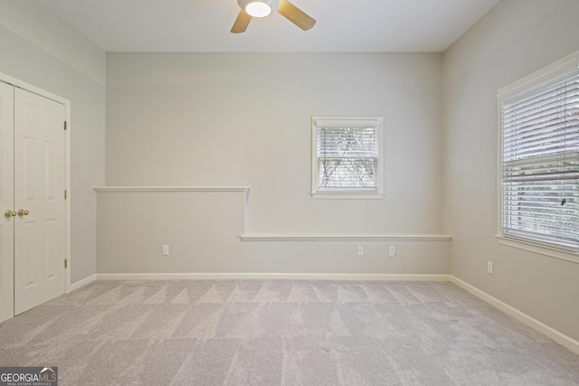 carpeted spare room featuring a healthy amount of sunlight, ceiling fan, and baseboards