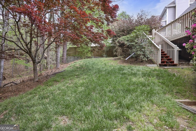 view of yard featuring fence, a deck, and stairs