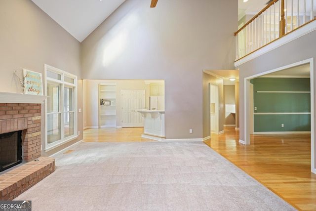 unfurnished living room featuring ceiling fan, a fireplace, carpet floors, wood finished floors, and baseboards