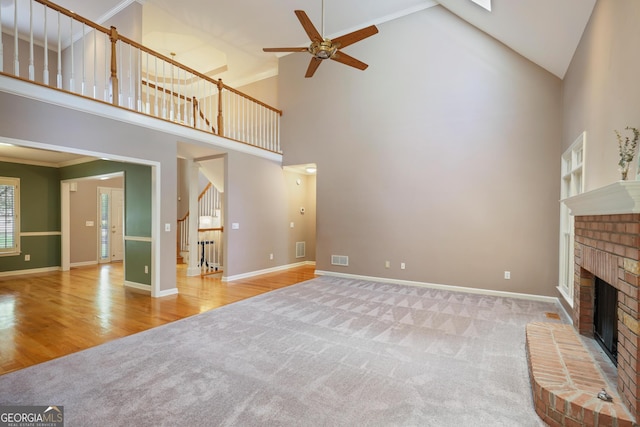 unfurnished living room with a ceiling fan, carpet floors, wood finished floors, a brick fireplace, and baseboards