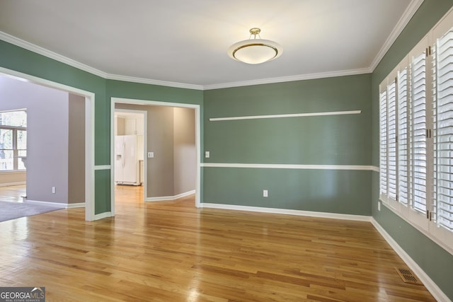 unfurnished room featuring visible vents, baseboards, crown molding, and wood finished floors