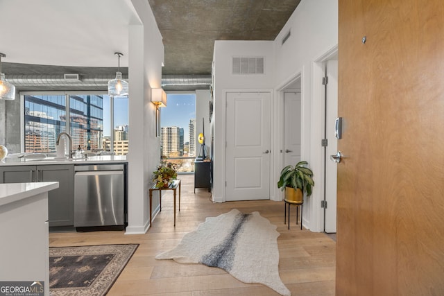 hall with a view of city, visible vents, light wood-style floors, and a sink