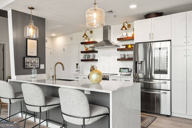 kitchen featuring tasteful backsplash, open shelves, a sink, ventilation hood, and stainless steel refrigerator with ice dispenser