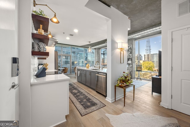 kitchen featuring open shelves, dishwasher, light wood finished floors, a sink, and visible vents