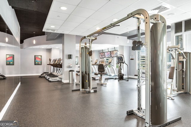 exercise room with baseboards, visible vents, and a paneled ceiling