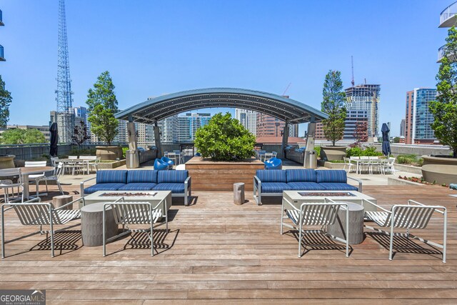 wooden deck featuring a view of city, an outdoor living space with a fire pit, and outdoor dining space