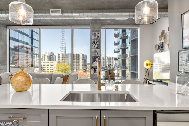 kitchen with light countertops, a sink, gray cabinetry, visible vents, and a city view