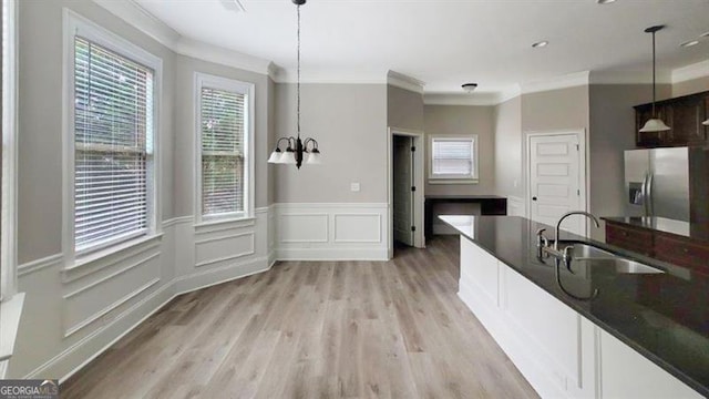 kitchen featuring dark countertops, stainless steel fridge, a sink, and ornamental molding