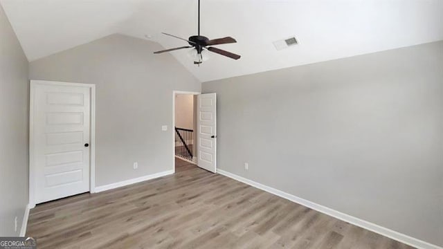 unfurnished bedroom featuring baseboards, visible vents, wood finished floors, and lofted ceiling