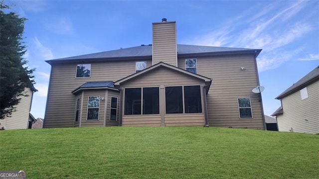rear view of house with a lawn, a chimney, and a sunroom