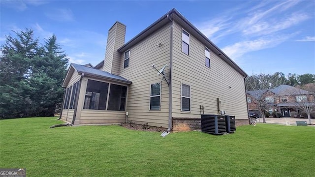 view of side of property with a sunroom, a yard, and a chimney