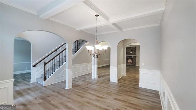 unfurnished dining area featuring a decorative wall, a notable chandelier, beam ceiling, and coffered ceiling