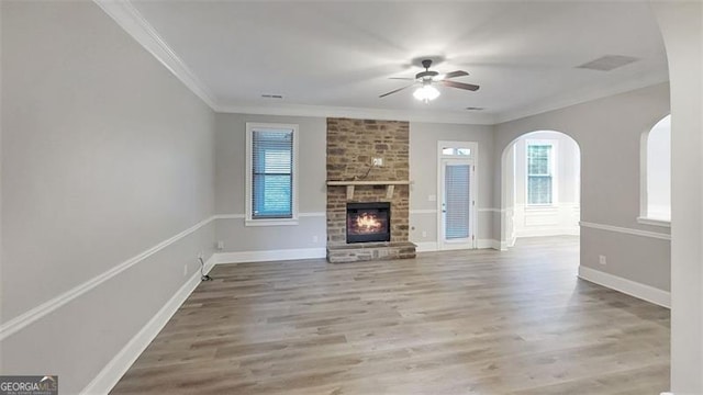 unfurnished living room with crown molding, ceiling fan, a wealth of natural light, and wood finished floors