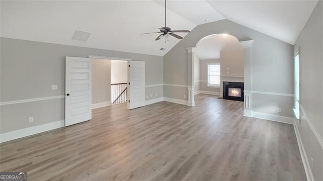 unfurnished living room with ceiling fan, vaulted ceiling, a glass covered fireplace, and wood finished floors