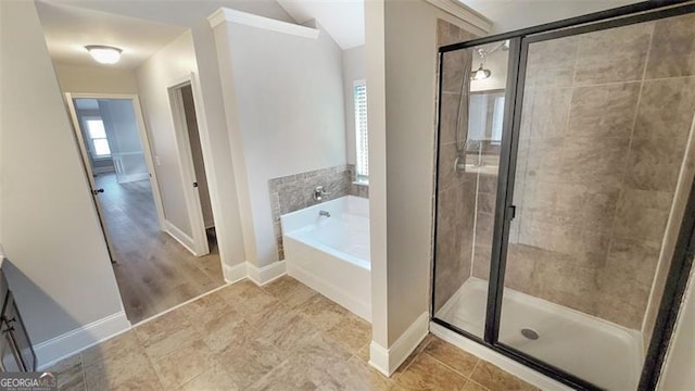 bathroom with a garden tub, baseboards, and a stall shower
