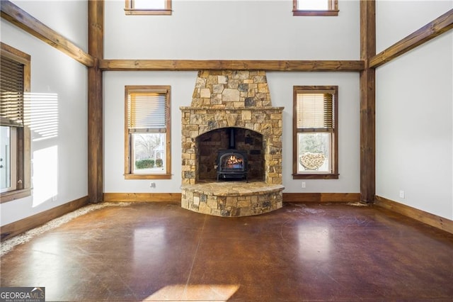 1759 Moccasin Gap Rd, Lula, GA 30554 - unfurnished living room featuring concrete flooring, a wood stove, plenty of natural light, a towering ceiling, and baseboards