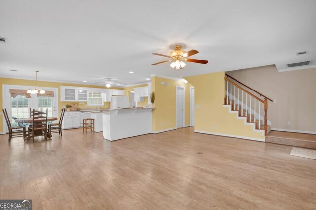 548 Sand Hill Rd, Brooklet, GA 30415 - unfurnished living room featuring stairs, light wood-type flooring, ceiling fan with notable chandelier, visible vents, and recessed lighting